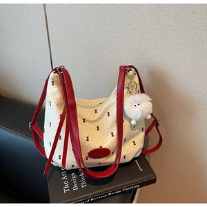 Close-up of cream canvas tote bag with red bow patterns and plush monster charm