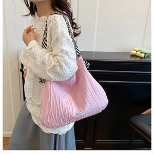 Gros plan d'un sac fourre-tout rose plissé avec bandoulière rayée sur un modèle