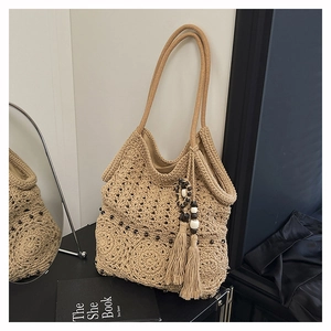 Detail of hollow crochet tote bag with long tassels and wooden beads on shoulder strap