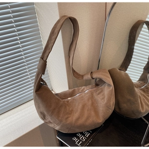 Detail of brown suede croissant bag showing pleated stitching and silver zipper closure