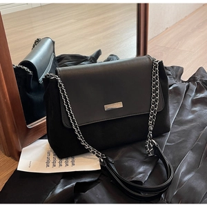 Detail view of black vintage underarm bag featuring silver chain strap and metal logo lettering