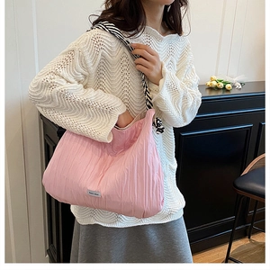 Détail du sac matelassé rose avec bandoulière rayée porté à l'épaule du mannequin