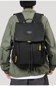 Close-up of canvas travel backpack with yellow zippers and drawstring flap closure