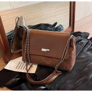Close-up of vintage brown crossbody bag with leather and suede texture and chain strap