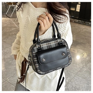 Details des kleinen Crossbody-Tasche mit kariertem Stoff und schwarzem Lederhandgriff