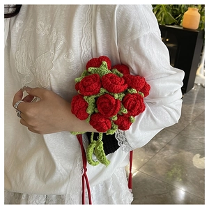 Detailed close-up of handmade crochet red roses and green leaves on a stylish mini bag