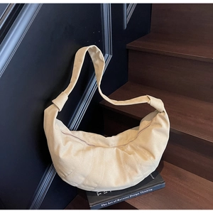 Detail of light beige canvas croissant bag featuring soft texture and decorative shoulder knots
