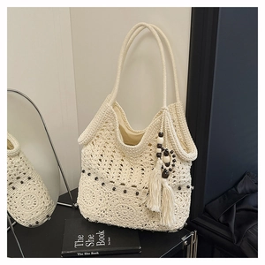 Close-up of white crochet tote bag with floral patterns, tassels and wooden beads