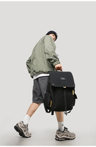 Detail of black outdoor backpack with yellow contrast zippers and drawstring closure