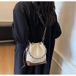 Detail of color-block drawstring bucket bag with silver chain and woven texture