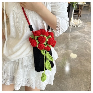 Detailed shot of handmade crochet phone bag with 3D red rose flowers and green leaves