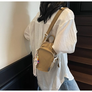 Detailed back view of khaki nylon sling bag with adjustable strap and beaded charm