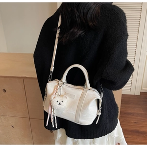 Detailed view of white minimalist pillow bag with plush bear charm and woven rope accent