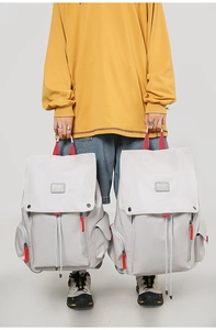 Detail of off-white canvas backpack featuring red handle and drawstring closure system