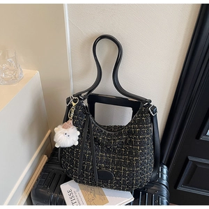 Detail of black tweed tote bag with gold thread texture and plush monster charm