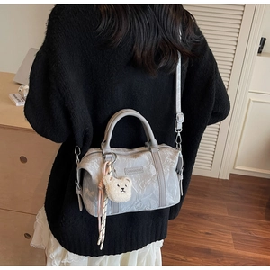 Chic light gray Boston bag with pleated texture and plush bear pendant shown on model