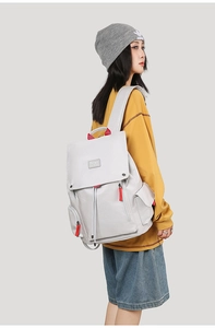 Detailed view of grey travel backpack with red zipper pulls and drawstring closure
