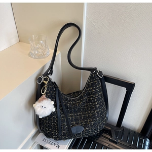 Detail of black tweed hobo bag featuring a cute white plush monster keychain charm