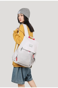 Side view of a grey canvas backpack with red accents shown on a model's back