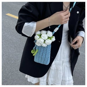 Detail view of handcrafted sky blue crochet bag with white floral embroidery and strap