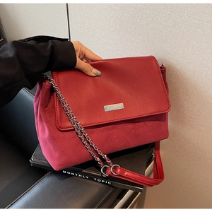 Close-up of red leather and suede texture on bag with metal chain strap and YOUBER logo