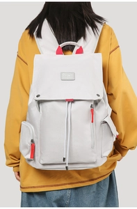 Detail of grey canvas backpack with red zipper accents and drawstring closure
