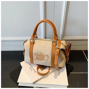 Detail der Boston-Tasche aus beigem Wildleder mit braunem Lederbesatz und Stickerei