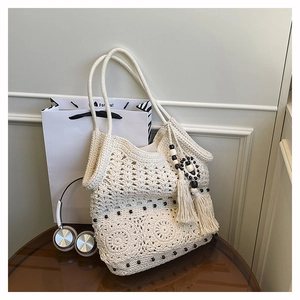 Close-up of cream crochet tote bag featuring intricate wave patterns and black bead accents