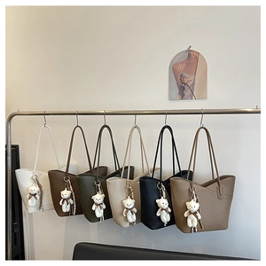 Reihe bunter Tote-Bags aus Kunstleder mit Litschi-Maserung und niedlichem Bären-Anhänger
