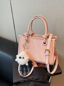 Pink PU leather bucket bag with knot handle and a cute white plush monster keychain