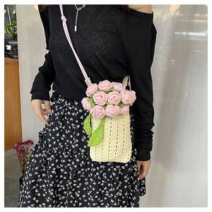 Close-up of handmade crochet mini crossbody bag with 3D pink roses and green leaves