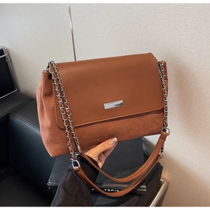 Detail showing brown leather and suede texture with silver metal chain on shoulder bag
