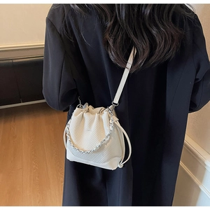 Detail of white drawstring bucket bag with textured leather and silver chain strap