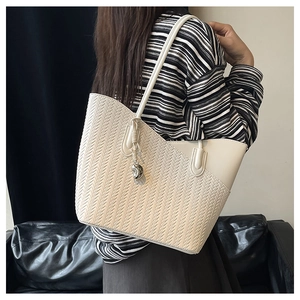 Macro detail of beige woven texture and metallic charm on large commuter tote bag