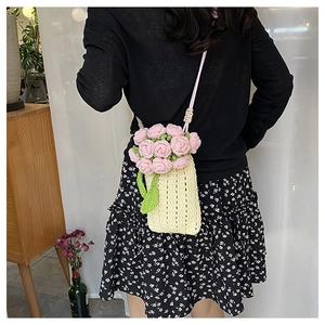 Close-up of handmade crochet rose bag showing knit texture and compact phone-sized fit