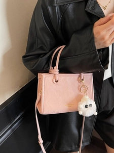 Pink leopard bucket bag with plush charm and adjustable strap shown on model shoulder