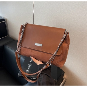 Detail of a brown patchwork shoulder bag with silver chain and metal brand plate