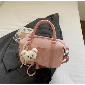Detail of pink Boston bag with brand tag, plush bear charm and woven rope decoration