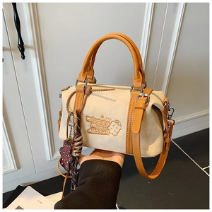Detail der beige Boston Tasche mit Ledergriffen und niedlichem Bären-Anhänger
