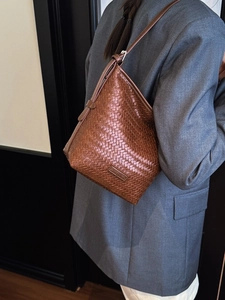 Brown woven leather bucket bag with a chic minimalist design and fine shoulder strap