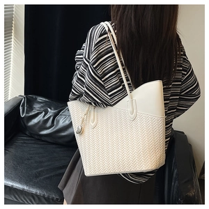 Detailed view of woven texture on a white tote bag with a silver heart charm