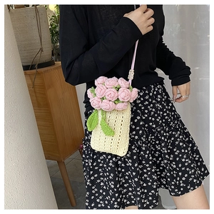 Close-up of handmade crochet flower detail on a cream knitted crossbody phone bag