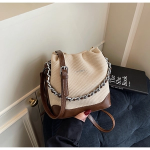 Detail of contrast stitch bucket bag featuring woven texture and silver chain strap