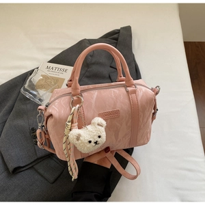 Detail of pink cylinder bag with crinkled texture, bear charm and woven rope accent