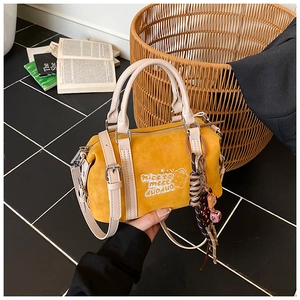 Detail der gelben Boston-Tasche mit Cartoon-Stickerei und Würfelanhänger-Dekor