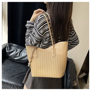 Detail of light khaki tote bag featuring woven herringbone texture and PU leather contrast