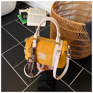 Nahaufnahme der gelben Boston-Tasche aus Wildleder mit Stickerei und gewebtem Anhänger