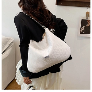Détail du sac cabas blanc plissé avec bandoulière tressée porté par un mannequin