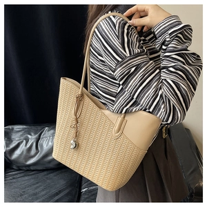 Detail of elegant beige tote bag featuring woven texture and heart-shaped metal charm