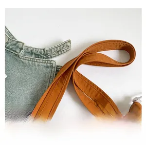 Close-up of caramel orange tote bag straps with reinforced stitching and nylon texture
